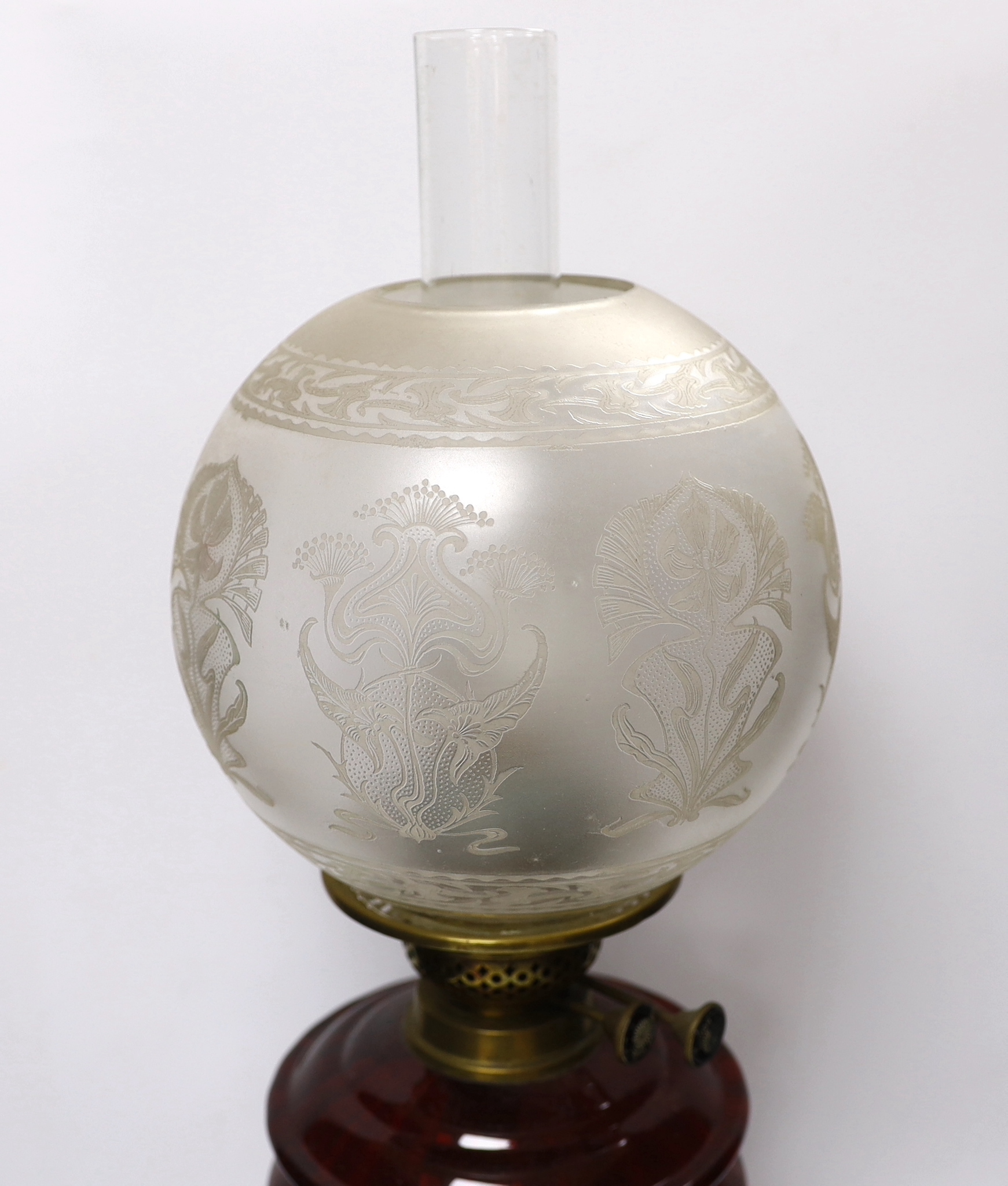 Three oil lamps with glass reservoirs and shades, one with Art Nouveau style base, 62cm high